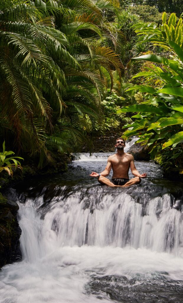 Hombre sentado meditando en una cascada en Costa Rica